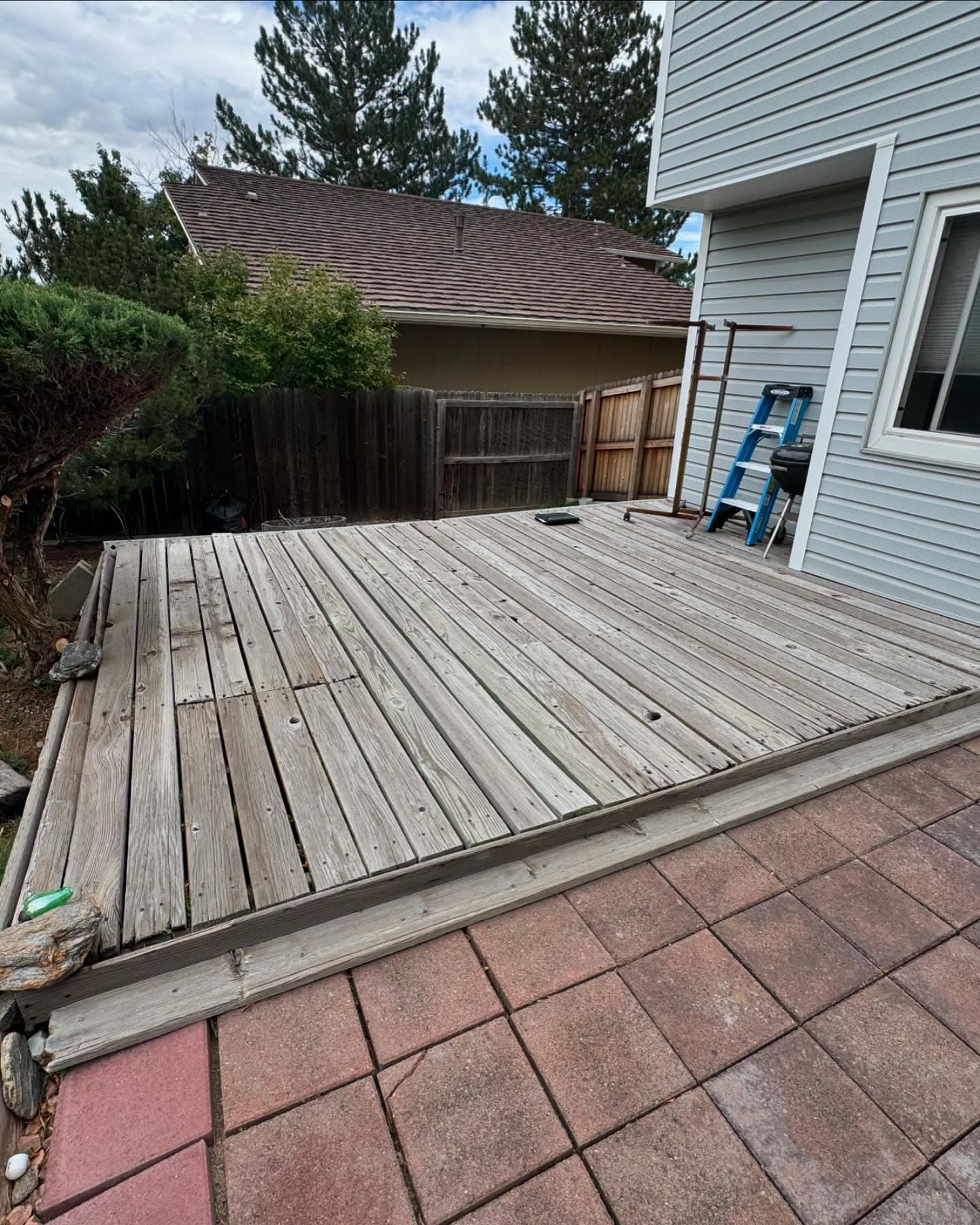 Weathered pressure-treated wood deck with split, cupped boards before demolition