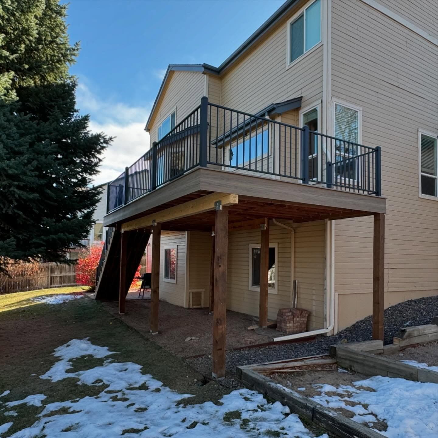 Two-story composite deck with black aluminum railing and cedar posts over a covered lower patio