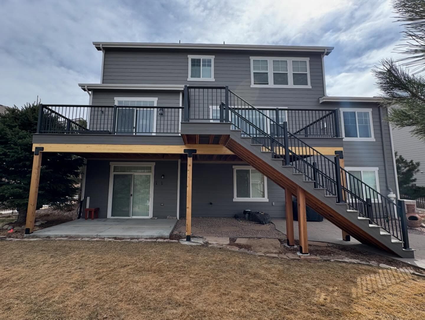 Two-story deck on cedar posts with black railing and a covered patio underneath