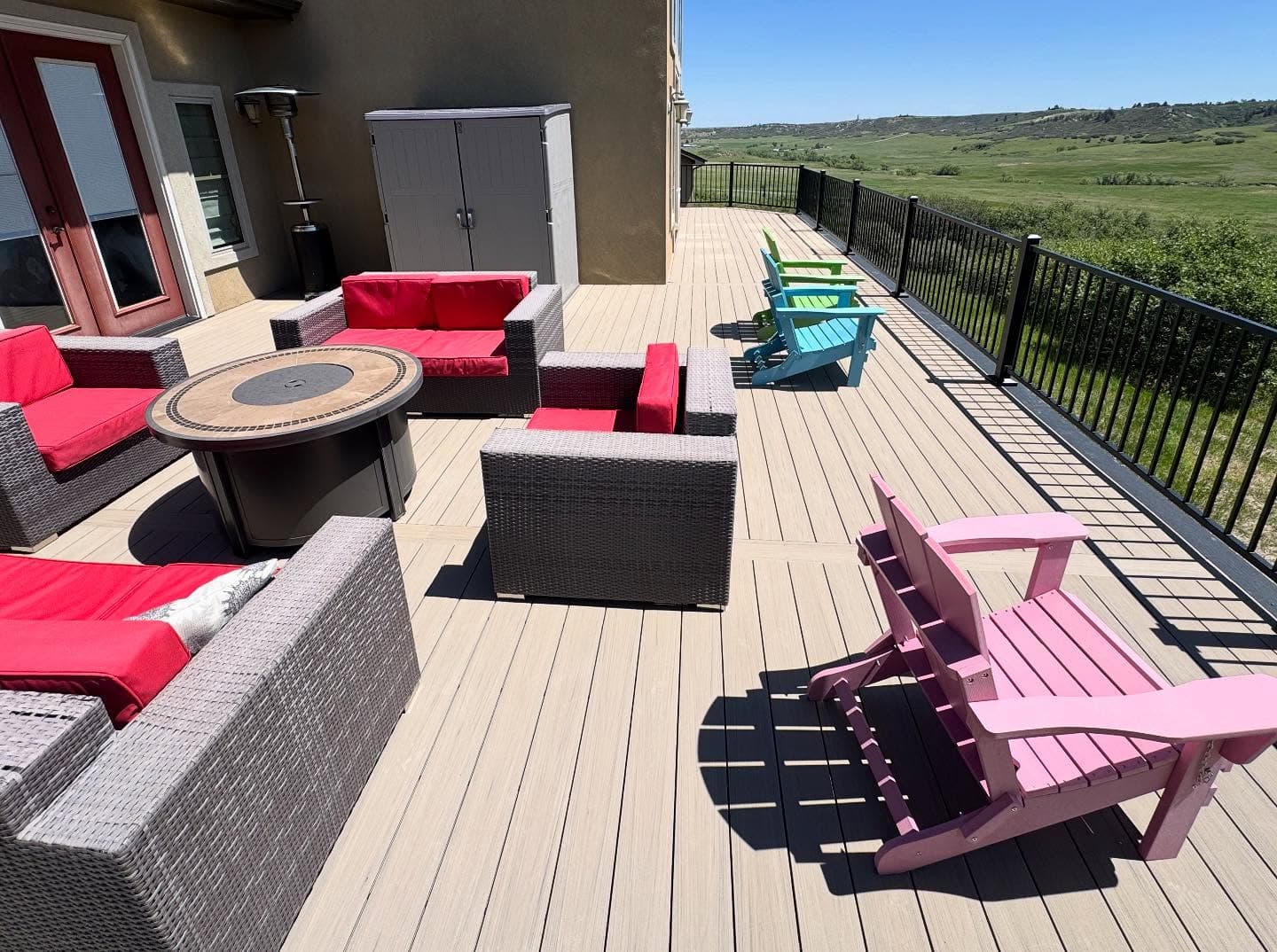 Narrow composite porch deck with black aluminum railing running along a green two-story home