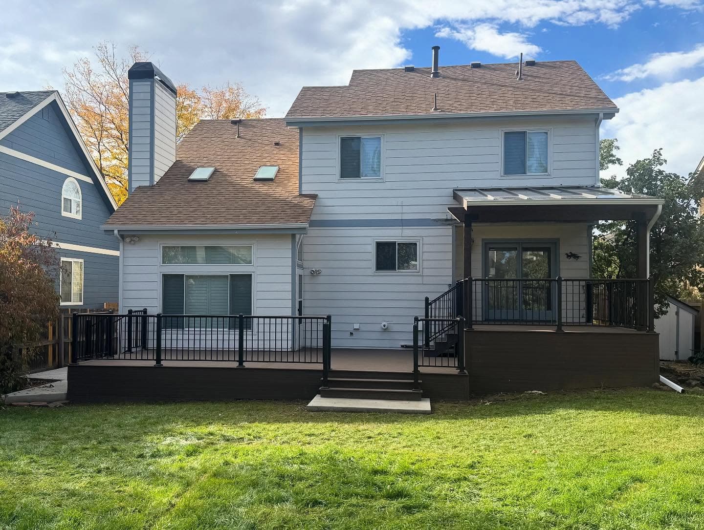 Ground-level composite deck with black railing and a covered section with a standing-seam metal roof